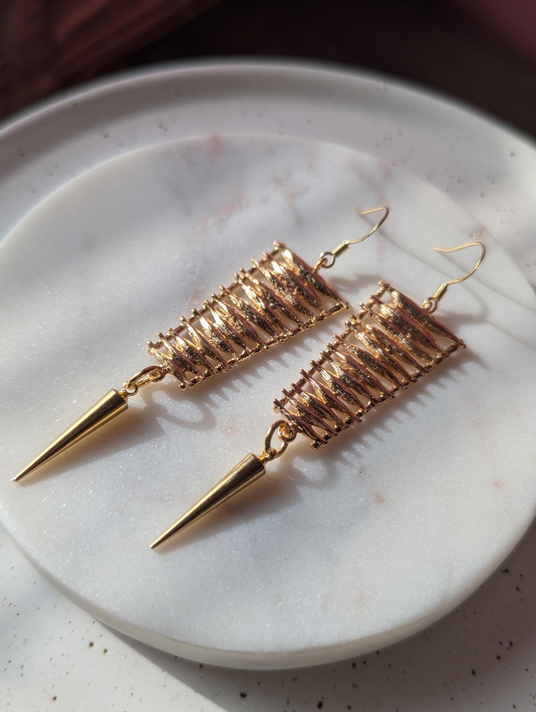 Gold ladder earring with gold spike dangle.